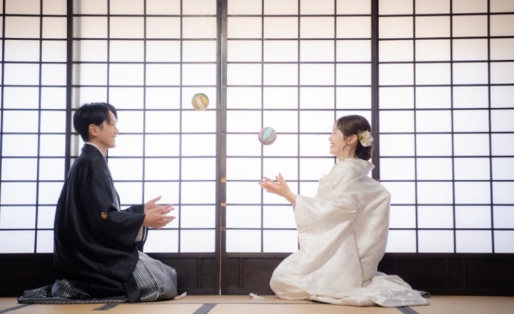 Doudantei｜和装姿のカップルが和室で向かい合ってまりで遊んでいるイメージ