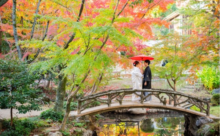 Yokiso｜和装姿のカップルが紅葉の下の橋の上で撮影をしているイメージ