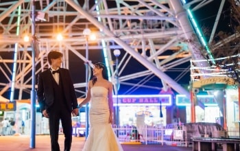 Nagoya Port Sea Train Land｜洋装姿のカップルが夜の遊園地で観覧車を背景に撮影をしているイメージ